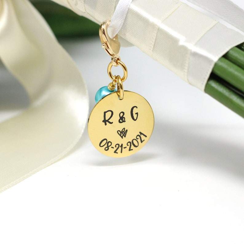 personalized bridal bouquet charm in gold with aqua pearl attached to bouquet