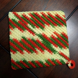 May include: A crocheted pot holder with a diagonal striped pattern in red, green, and yellow.