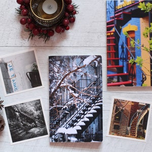 A winter notebook featuring a black and white photograph of Montreal's snow-covered spiral walk-up stairs with parked bicycles covered in snow. The notebook is surrounded by other Montreal notebooks and mini prints that can be framed or sent as cards.

The hand-bound notebooks measure 5x8 inches. They contain 48 pages of cream-white acid free paper with a smooth finish. The matte cover is smooth and scuff-resistant!

Each notebook comes with an insert containing 15 insightful journaling prompts!
