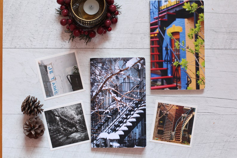 A winter notebook featuring a black and white photograph of Montreal's snow-covered spiral walk-up stairs with parked bicycles covered in snow. The notebook is surrounded by other Montreal notebooks and mini prints that can be framed or sent as cards.

The hand-bound notebooks measure 5x8 inches. They contain 48 pages of cream-white acid free paper with a smooth finish. The matte cover is smooth and scuff-resistant!

Each notebook comes with an insert containing 15 insightful journaling prompts!