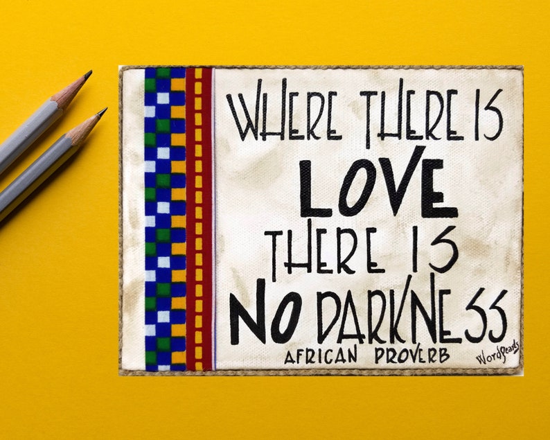 May include: A white canvas with a black and white African proverb that reads "Where there is love there is no darkness." The canvas is bordered with a colorful patterned fabric and has a "WordReads" logo in the bottom right corner.