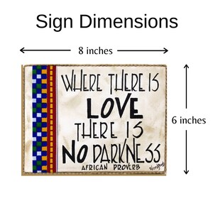 May include: A wooden sign with a beige background and a colorful patterned border. The sign reads "Where there is love there is no darkness" and "African Proverb". The sign measures 8 inches wide and 6 inches tall.