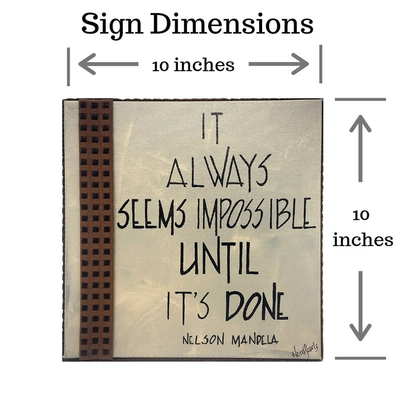 May include: A 10-inch square wooden sign with a brown and white checkered border. The sign has a white background with black text that reads "IT ALWAYS SEEMS IMPOSSIBLE UNTIL IT'S DONE - NELSON MANDELA".