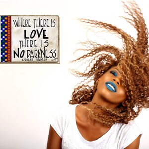 May include: A woman with long, curly, light brown hair is smiling with her head tilted back. She is wearing blue lipstick and blue eyeshadow. The background is white with a sign that reads "Where there is love there is no darkness. African proverb."