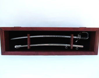 May include: A wooden display case with a black velvet interior, showcasing two swords with silver blades and ornate handles.