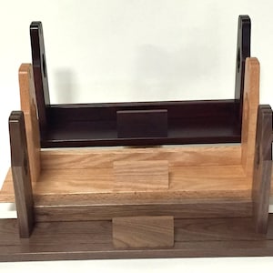 Puede incluir: Un soporte de madera de tres niveles con un nivel superior marr&oacute;n oscuro, un nivel intermedio marr&oacute;n claro y un nivel inferior marr&oacute;n oscuro. El soporte est&aacute; dise&ntilde;ado para sostener espadas u otros objetos largos.