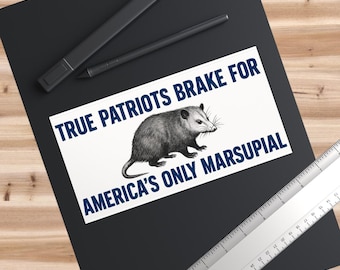 May include: A rectangular sticker with the text "TRUE PATRIOTS BRAKE FOR AMERICA'S ONLY MARSUPIAL" in blue. The sticker features a detailed illustration of an opossum in black and white.