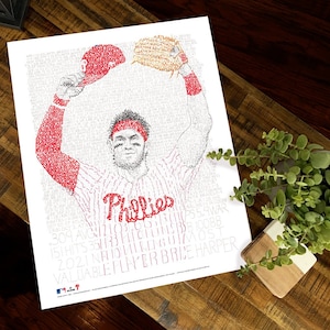 May include: A white print featuring a baseball player in a Phillies uniform, with the word "Phillies" in red script. The image is composed of text, including player stats and the words "Valuable Player Brice Harper."