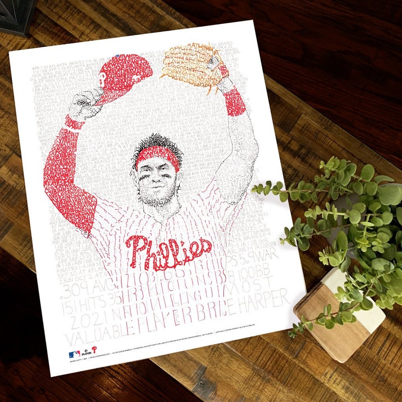 May include: A white print featuring a baseball player in a Phillies uniform, with the word "Phillies" in red script. The image is composed of text, including player stats and the words "Valuable Player Brice Harper."