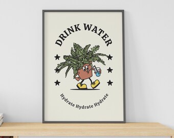 May include: A black framed print with a cartoon illustration of a potted plant holding a glass of water. The text on the print reads "Drink Water Hydrate Hydrate Hydrate". The print is displayed on a light wood shelf with books and a small potted plant.