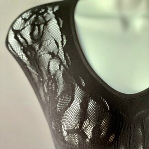 May include: Black sleeveless top with a lace overlay. The lace is a delicate floral pattern.
