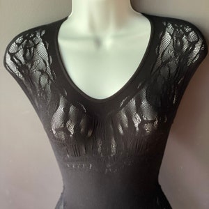 May include: Black lace top with a v-neckline and short sleeves. The lace is a delicate floral pattern.
