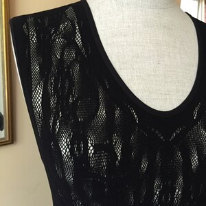 May include: Black sleeveless top with a delicate lace pattern. The top has a scoop neck and is made of a sheer fabric.
