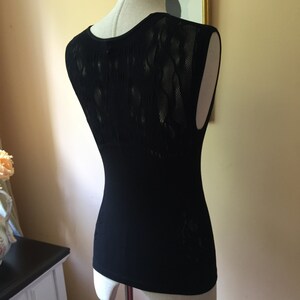 May include: Black sleeveless top with a lace back panel. The top is fitted and has a scoop neck.
