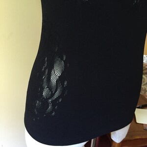 May include: Black sleeveless top with a lace panel on the side.