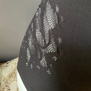 May include: Black sleeveless top with a floral lace design on the side.