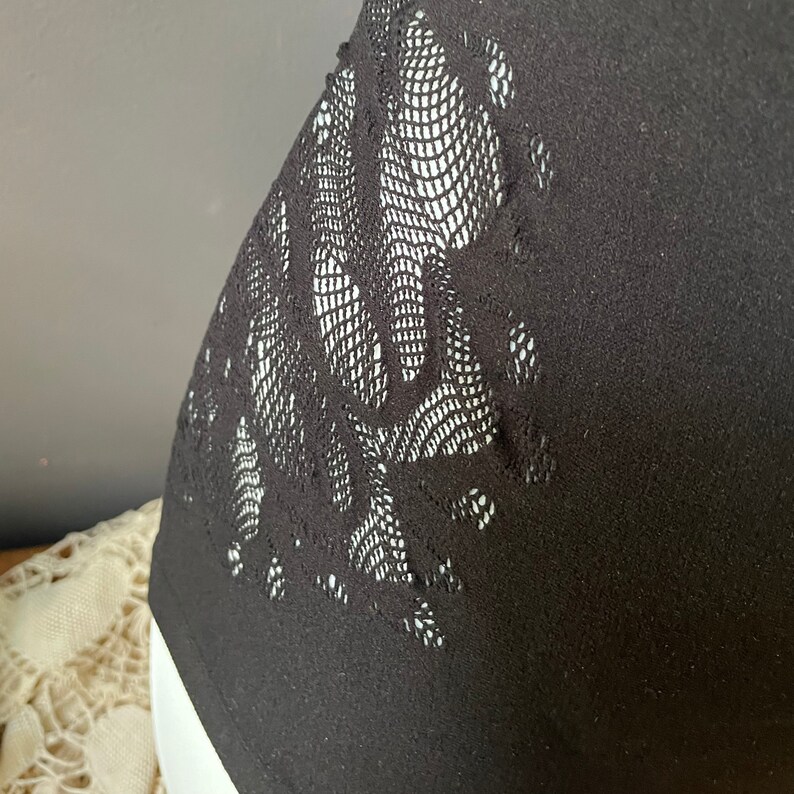 May include: Black sleeveless top with a floral lace design on the side.