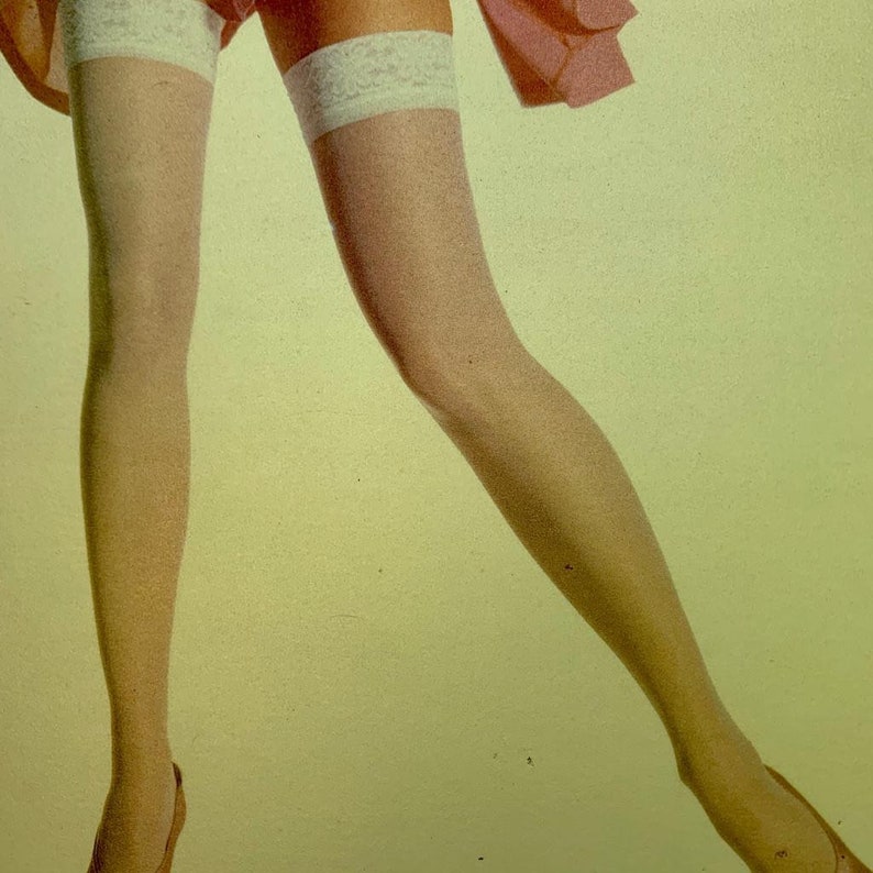 May include: A pair of sheer, light-colored stockings featuring white lace-trimmed tops. The stockings extend from the upper thigh down to the feet, showcasing a smooth, semi-transparent texture and a decorative floral pattern on the lace bands.