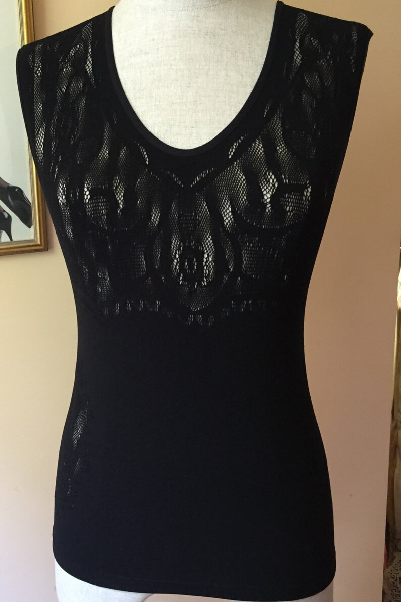 May include: Black sleeveless top with a lace pattern on the front. The top is made of a soft, stretchy fabric.