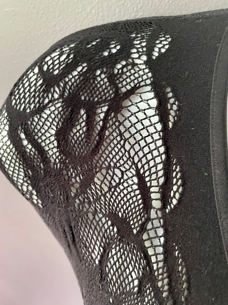 May include: Black lace fabric with a floral pattern. The fabric is sheer and has a delicate texture.