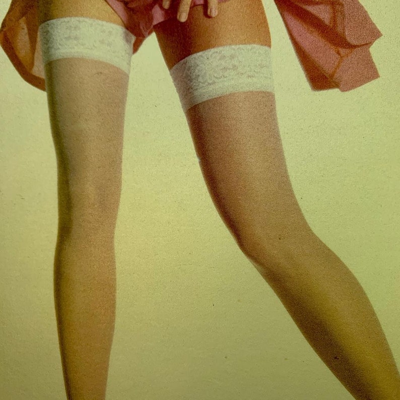 May include: A pair of sheer, light-toned stockings featuring wide, white lace-trimmed bands at the top. The stockings are worn with a pink garment visible at the upper thigh area, showcasing a classic hosiery design with detailed floral lace.