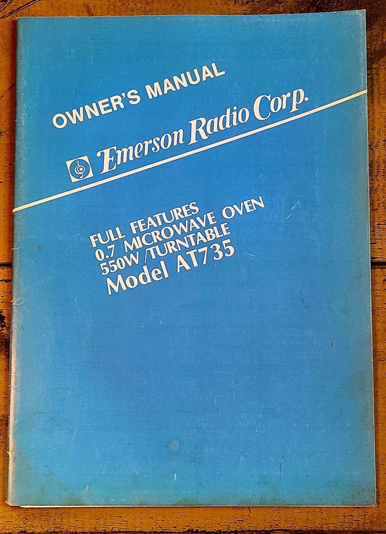 May include: Blue owner's manual for an Emerson Radio Corp. 0.7 cu ft microwave oven with a turntable. The model number is AT735.
