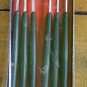 May include: A set of six silver fondue forks with black handles in a clear plastic box with a red and white interior. The box has a silver label that reads "Spring Made in Switzerland."