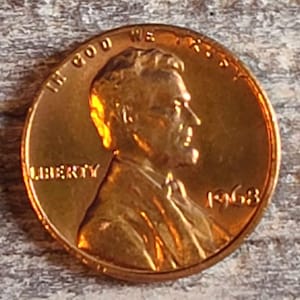 May include: A copper-colored 1968 US penny coin with the words "LIBERTY" and "IN GOD WE TRUST" and the year "1968" visible.