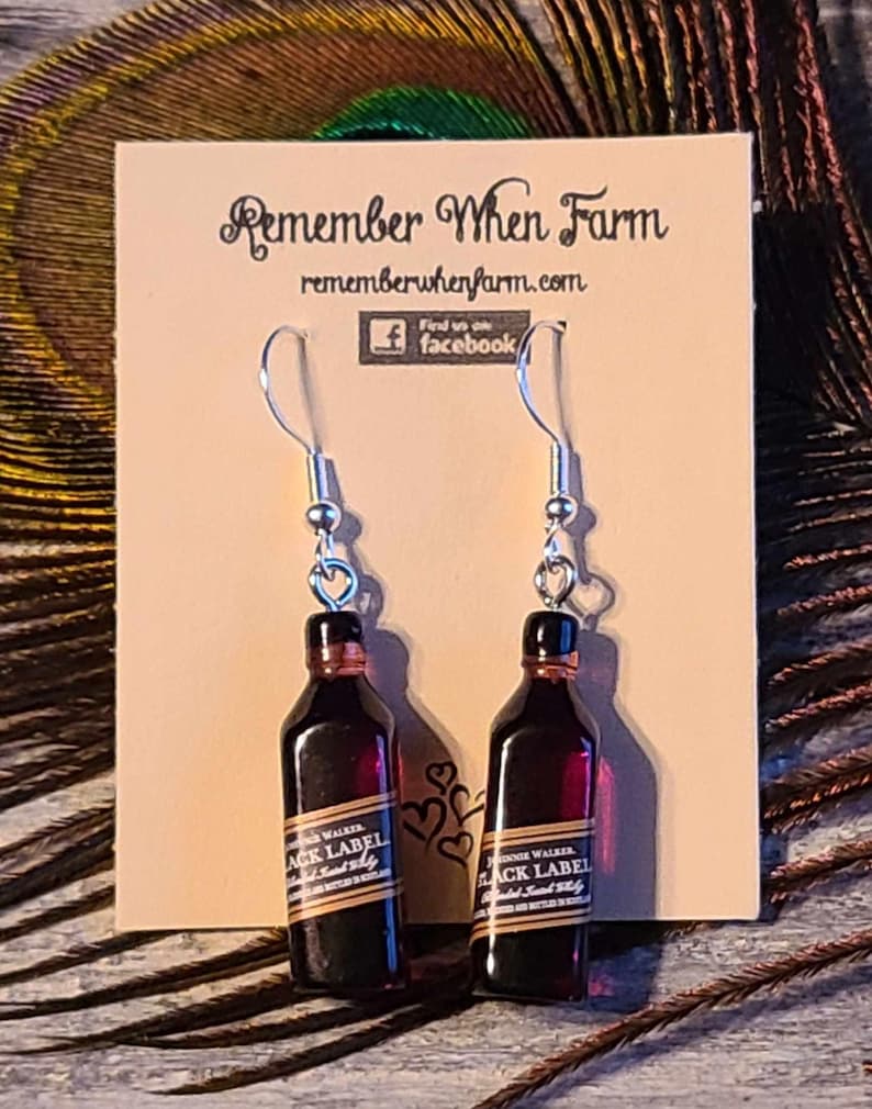 May include: A pair of silver dangle earrings with a miniature bottle of Johnnie Walker Black Label Scotch whisky charm. The earrings are displayed on a card with the text "Remember When Farm" and "rememberwhenfarm.com".