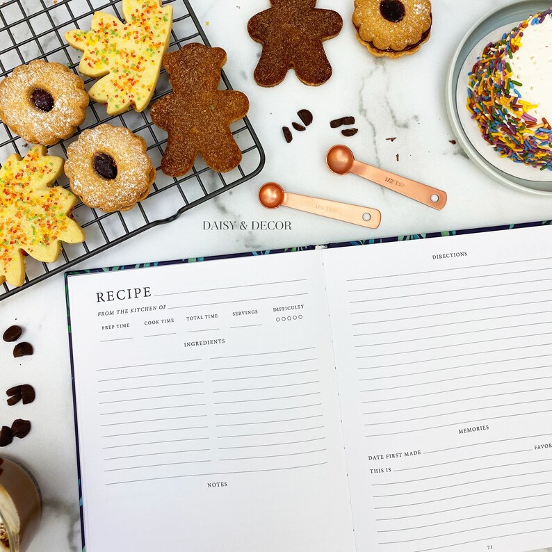 May include: A recipe journal with a black cover and a floral design. The journal has sections for prep time, cook time, total time, servings, difficulty, ingredients, notes, date first made, this is, and memories. The journal is open to a blank page with lines for writing.