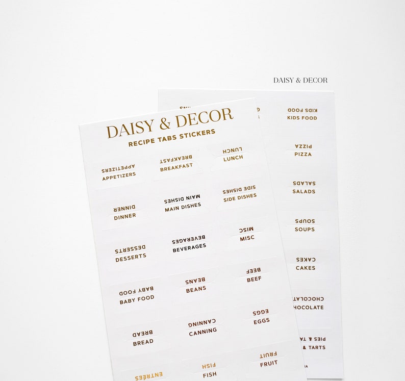 May include: A set of white recipe tabs with gold lettering. The tabs are labeled with different food categories, such as appetizers, breakfast, lunch, dinner, desserts, beverages, main dishes, side dishes, soups, salads, and more. The tabs are designed to help organize recipes in a binder or cookbook.