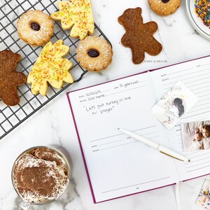 May include: A pink and white journal with a handwritten entry about a child's Thanksgiving dinner. The journal is open to a page with a date, place, and age. The page also has a photo of a child and a photo of two children. The journal is on a white surface with a cup of coffee, cookies, and a pen.