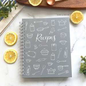 May include: Gray spiral bound recipe book with white illustrations of kitchen tools and the word "Recipes" on the cover.