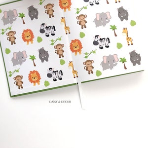 May include: A green and white journal with a repeating pattern of jungle animals, including lions, zebras, monkeys, elephants, hippos, and giraffes. The journal has a white ribbon bookmark and the text "DAISY & DECOR" printed on the bottom.