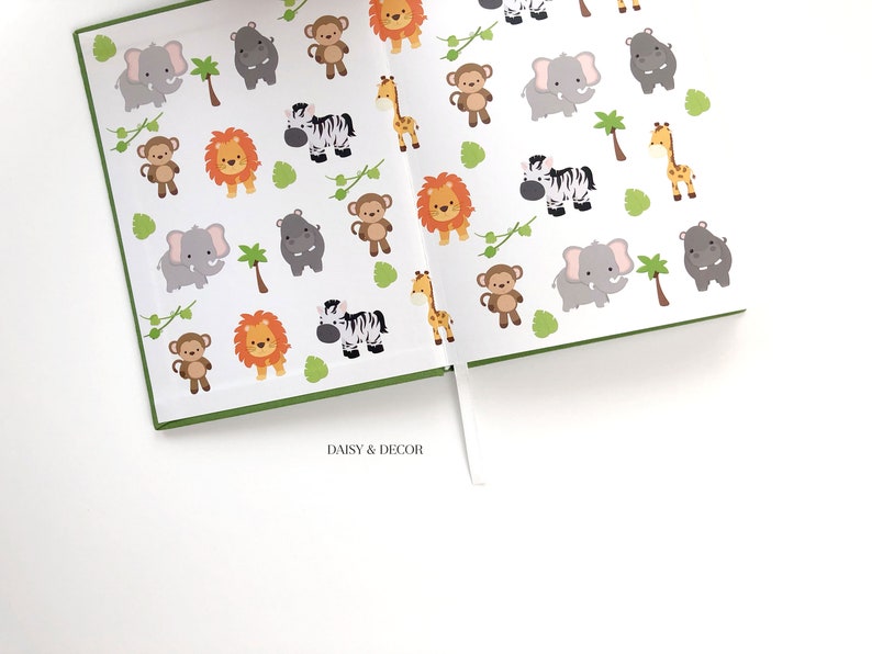 May include: A green and white journal with a repeating pattern of jungle animals, including lions, zebras, monkeys, elephants, hippos, and giraffes. The journal has a white ribbon bookmark and the text "DAISY & DECOR" printed on the bottom.