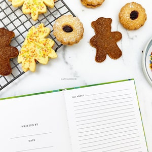 Puede incluir: Un cuaderno con una cubierta verde y las palabras "All About" escritas en la p&aacute;gina derecha. La p&aacute;gina izquierda tiene las palabras "Written By" y "Date" escritas en ella. Hay galletas en una rejilla de enfriamiento y un plato de chispas en el fondo.