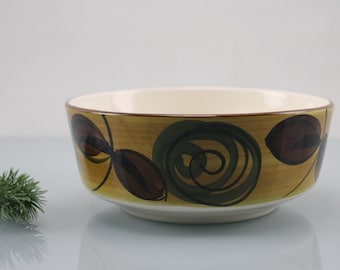May include: A ceramic bowl with a brown, green, and yellow floral design. The bowl is white on the inside.