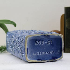 May include: Blue ceramic vase with a floral design and the text "263-21 W.GERMANY" on the bottom.