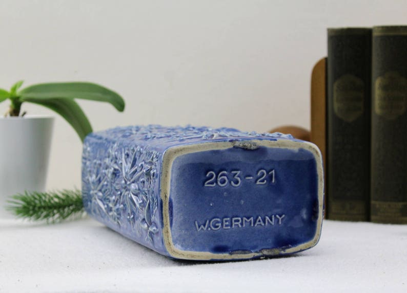 May include: Blue ceramic vase with a floral design and the text "263-21 W.GERMANY" on the bottom.