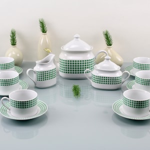 May include: A white tea set with a green and white checked pattern. The set includes a teapot, creamer, sugar bowl, and six cups and saucers.