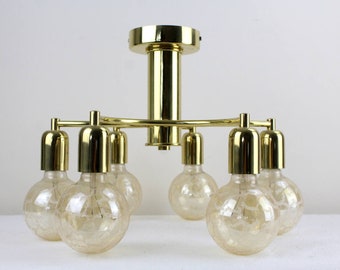 May include: A gold-toned ceiling light fixture with six light bulbs. The light bulbs are clear glass with a textured surface and are arranged in a circular pattern around the fixture.