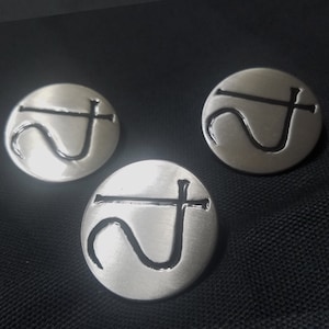May include: Three silver-colored metal pins with a black symbol of a stylized hook and cross.