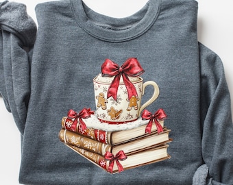 May include: A dark gray sweatshirt with a Christmas-themed design featuring a mug with a red bow, gingerbread men, and a stack of books with red bows.