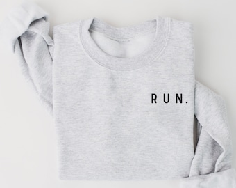 Puede incluir: Una sudadera gris con la palabra "RUN." impresa en negro en la parte delantera.