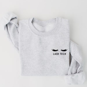 May include: A gray sweatshirt with the text "LASH TECH" and a pair of eyelashes printed on the front.