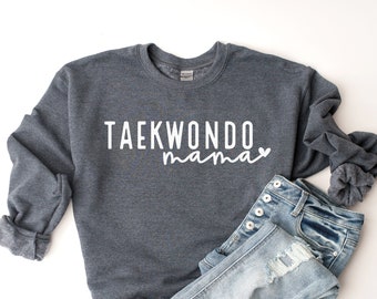 May include: A dark gray sweatshirt with the text "TAEKWONDO mama" in white lettering with a small heart symbol.