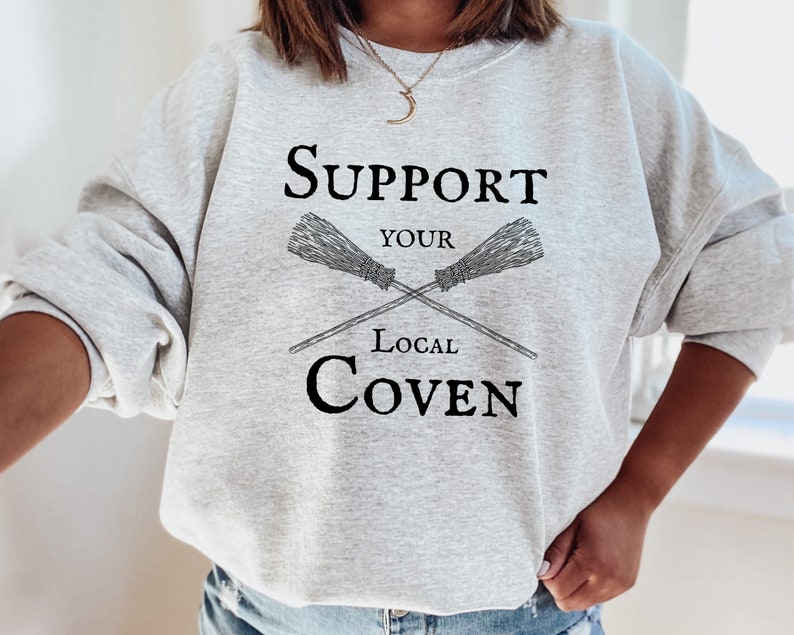 May include: Gray sweatshirt with the text "Support Your Local Coven" and a graphic of two crossed brooms.