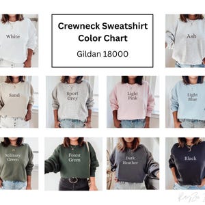 May include: Color chart for Gildan 18000 crewneck sweatshirts. The chart shows 10 different colors: white, ash, sand, sport grey, light pink, light blue, military green, forest green, dark heather, and black.