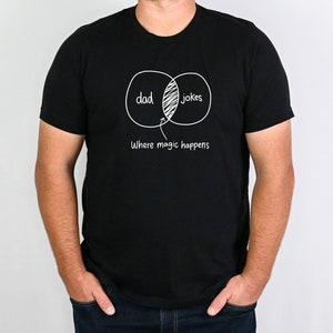 May include: A black t-shirt with a white graphic of two overlapping circles labeled "dad" and "jokes". The overlapping section of the circles is labeled "Where magic happens".