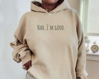 May include: A beige hoodie with the text "NAH, I'M GOOD." printed in black on the front.